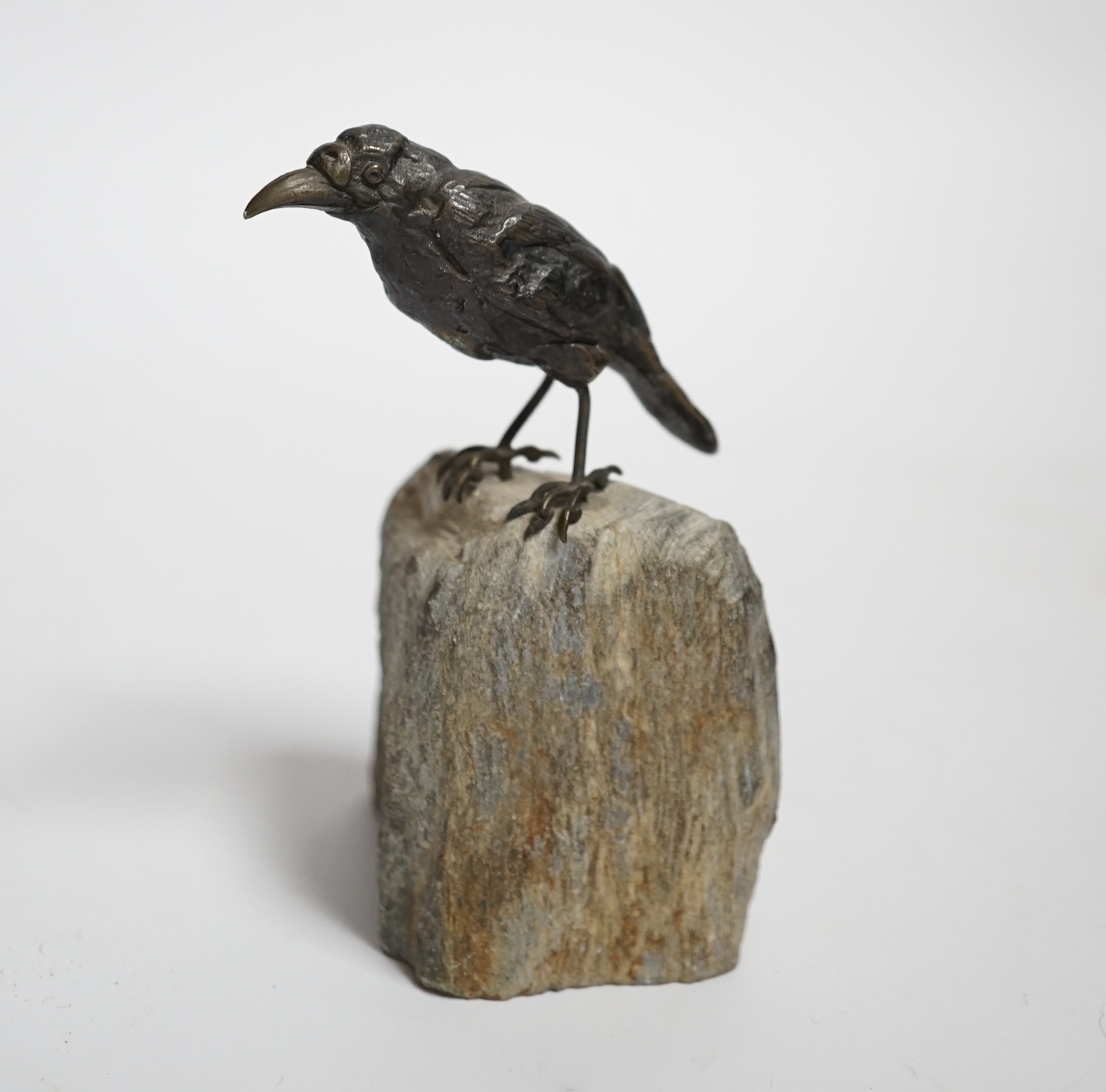 A cold painted bronze crow, raised on a stone base, 10cm high